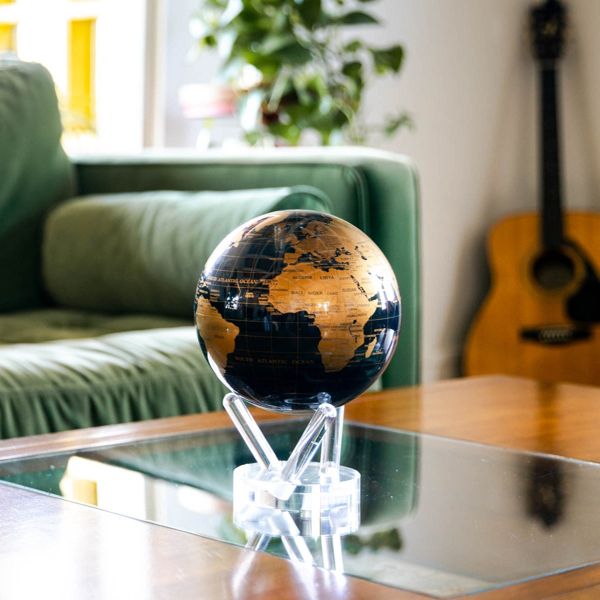 Jet Black & Gold MOVA Globe on a glass coffee table in a contemporary living room