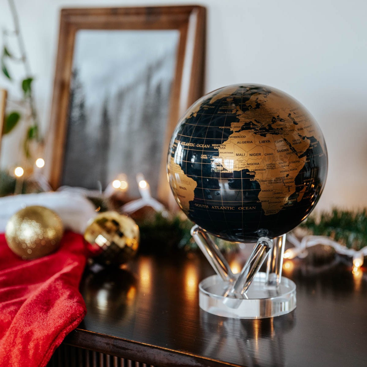 Jet Black & Gold MOVA Globe with gold continents displayed in a festive home setting