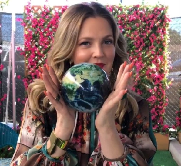 Woman holding an Earth with Clouds MOVA globe outdoors with vibrant floral backdrop and natural light