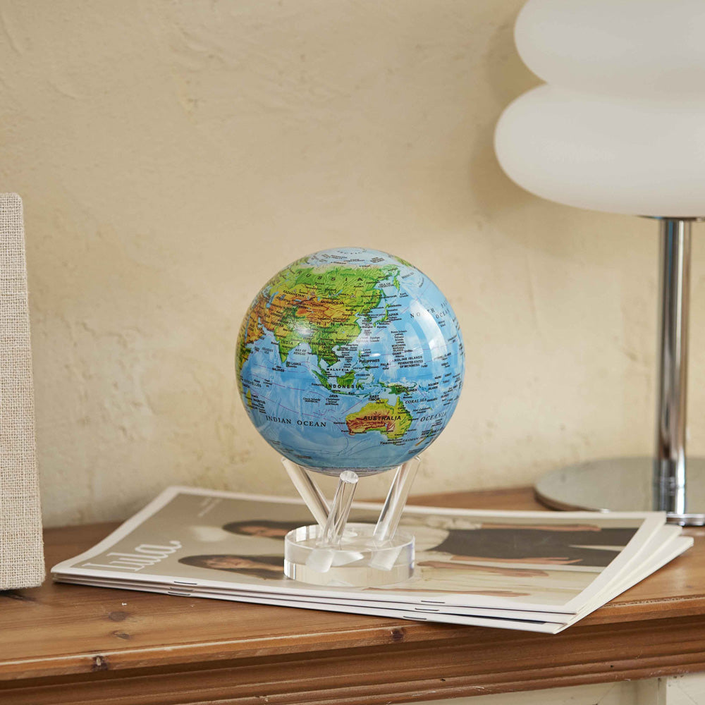 Ocean Blue Relief Map MOVA Globe displayed on console table with magazines