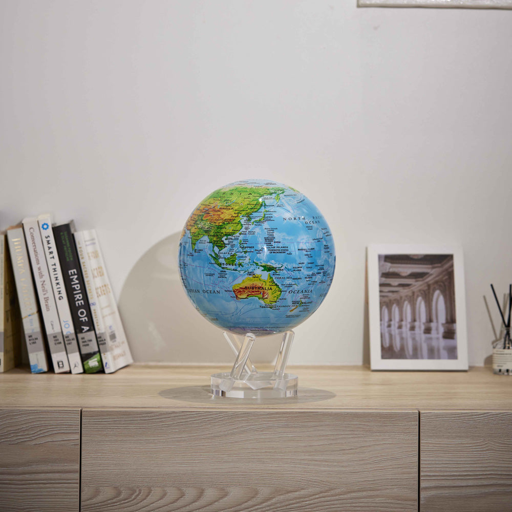 Ocean Blue Relief Map MOVA Globe on cabinet with books and framed artwork