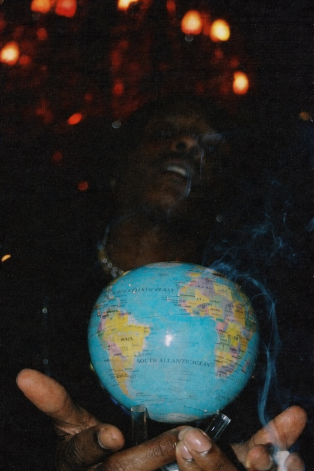 Blue political MOVA globe with acrylic base held in hands under dramatic ambient lighting