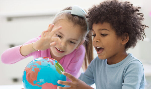 Children exploring a colorful globe together for fun educational learning and geography activities at home