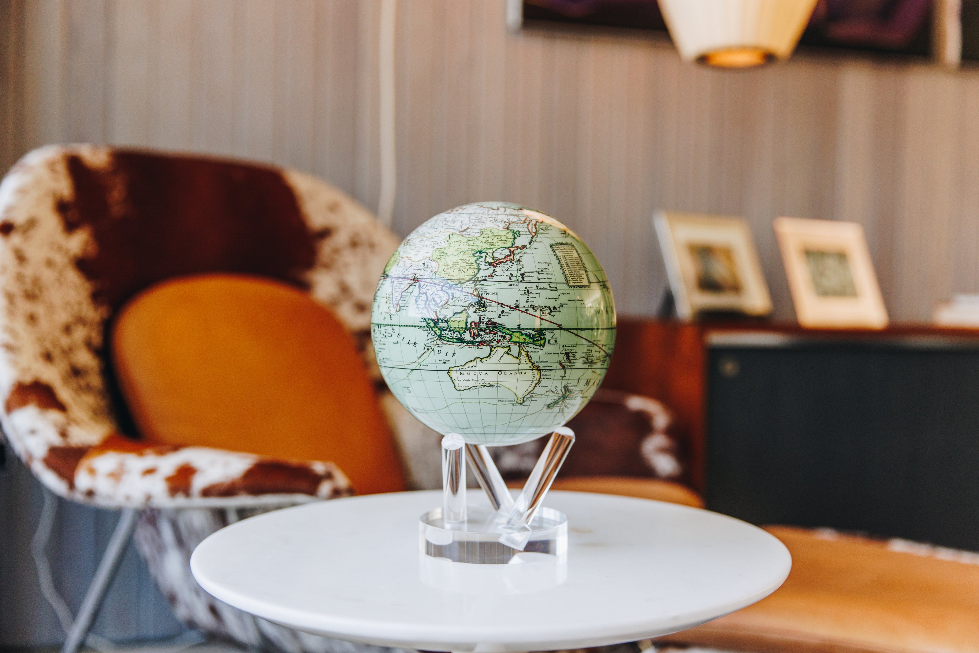 Antique terrestrial map MOVA globe with acrylic base on a white side table in a cozy modern lounge interior