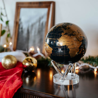 Jet Black &amp; Gold MOVA Globe with gold continents displayed in a festive home setting
