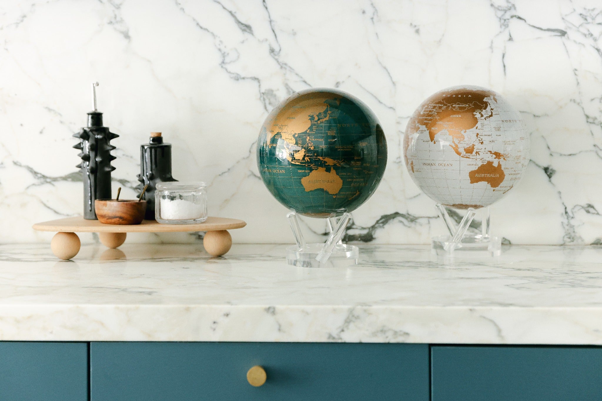 Metallic MOVA globes displayed on marble countertop with acrylic bases
