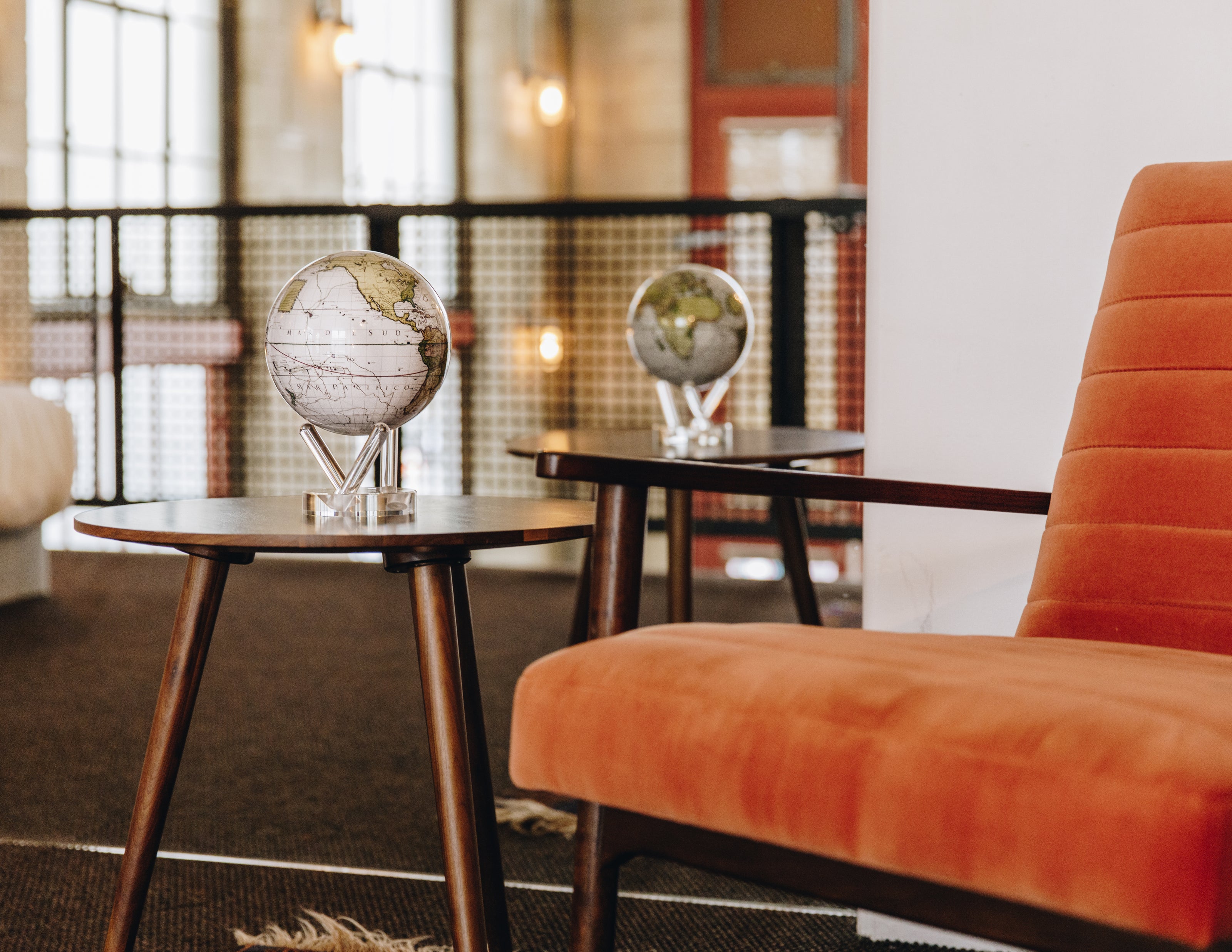Antique map MOVA globes with acrylic base styled on mid-century side tables in a modern loft interior