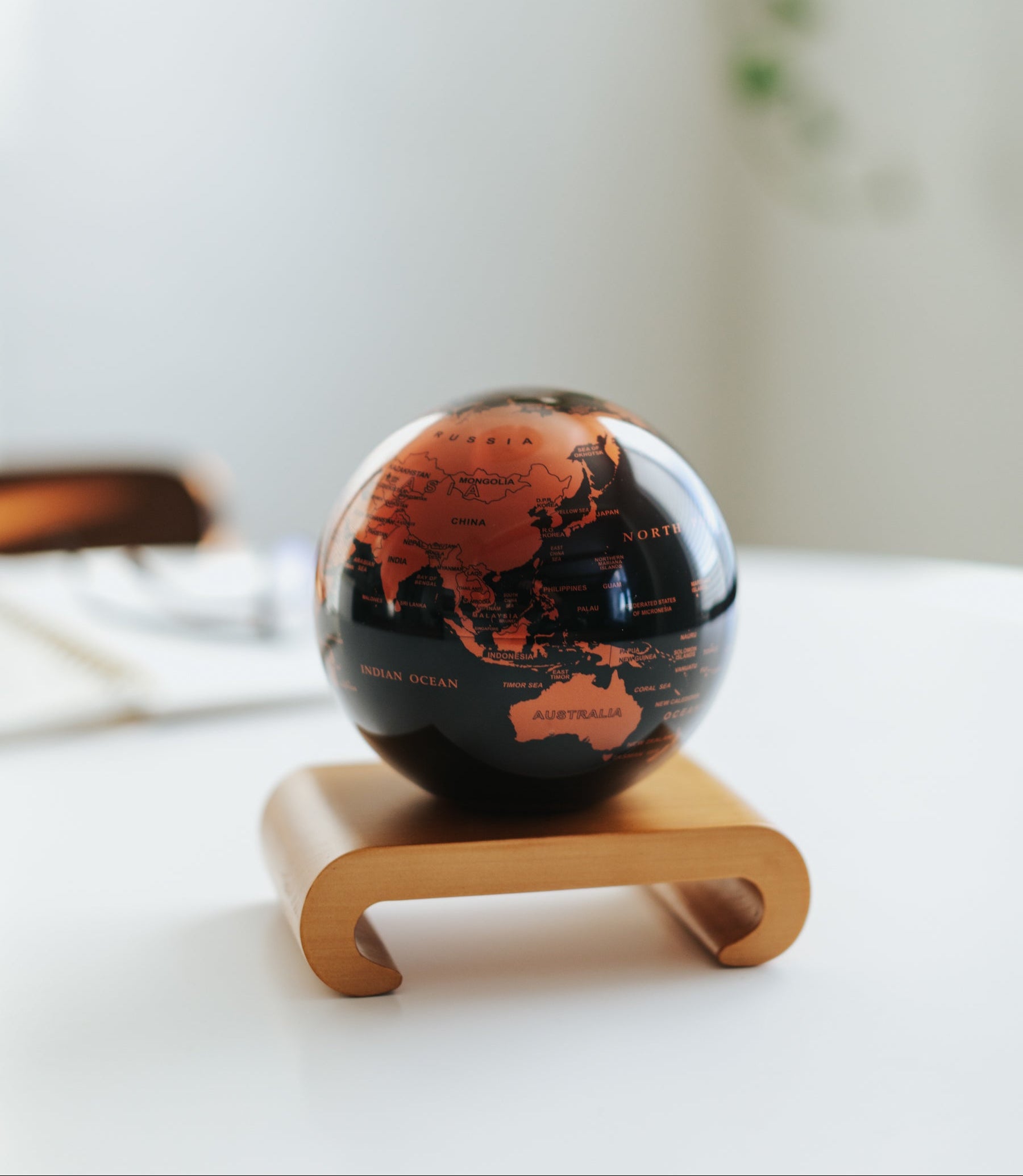Copper and black metallic MOVA globe on a wooden base in a bright minimalist interior