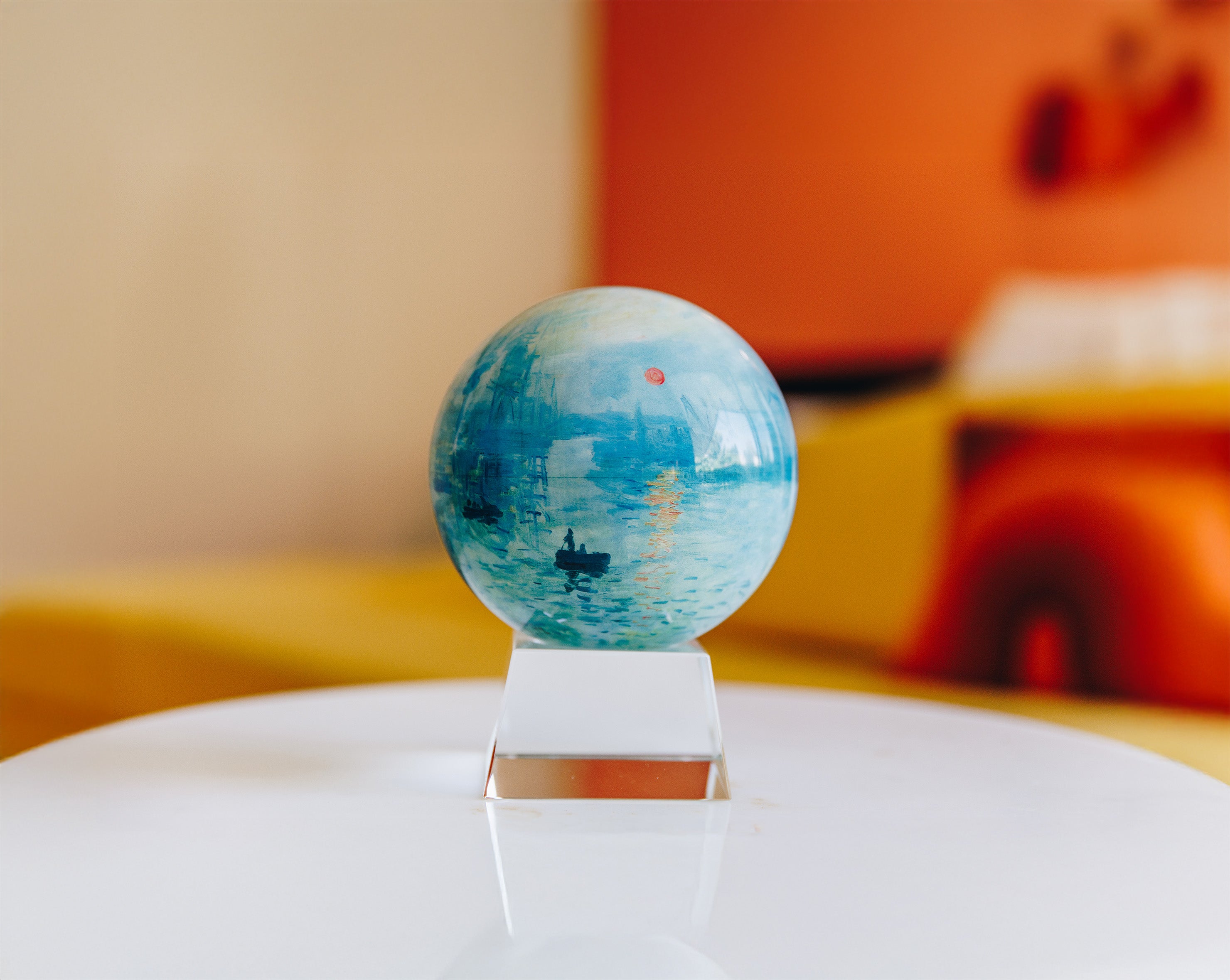 Monet-inspired art MOVA globe with crystal base on a white table in a colorful modern interior