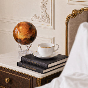 Mars MOVA globe displayed in an elegant luxury bedroom with classic decor, coffee cup and designer book accents