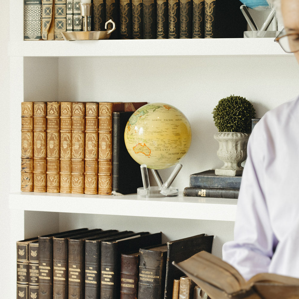 yellow Antique political world map MOVA globe displayed on a bookshelf in a classic luxury study with vintage book decor accents
