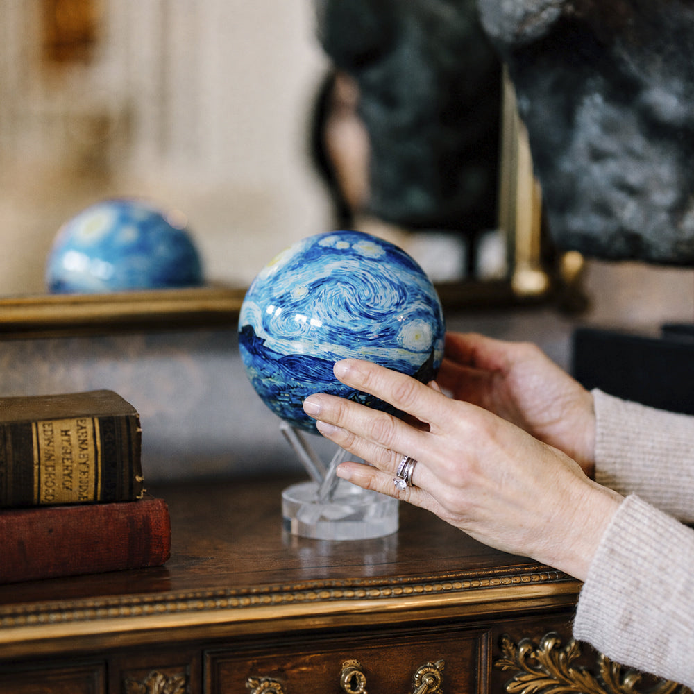 Starry Night MOVA globe displayed on acrylic base in an elegant luxury study with classic artistic decor styling