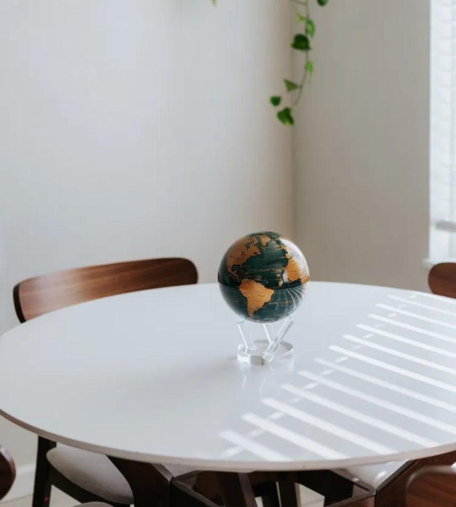 Green and Gold MOVA rotating globe on dining table, stylish home decoration and elegant conversation piece