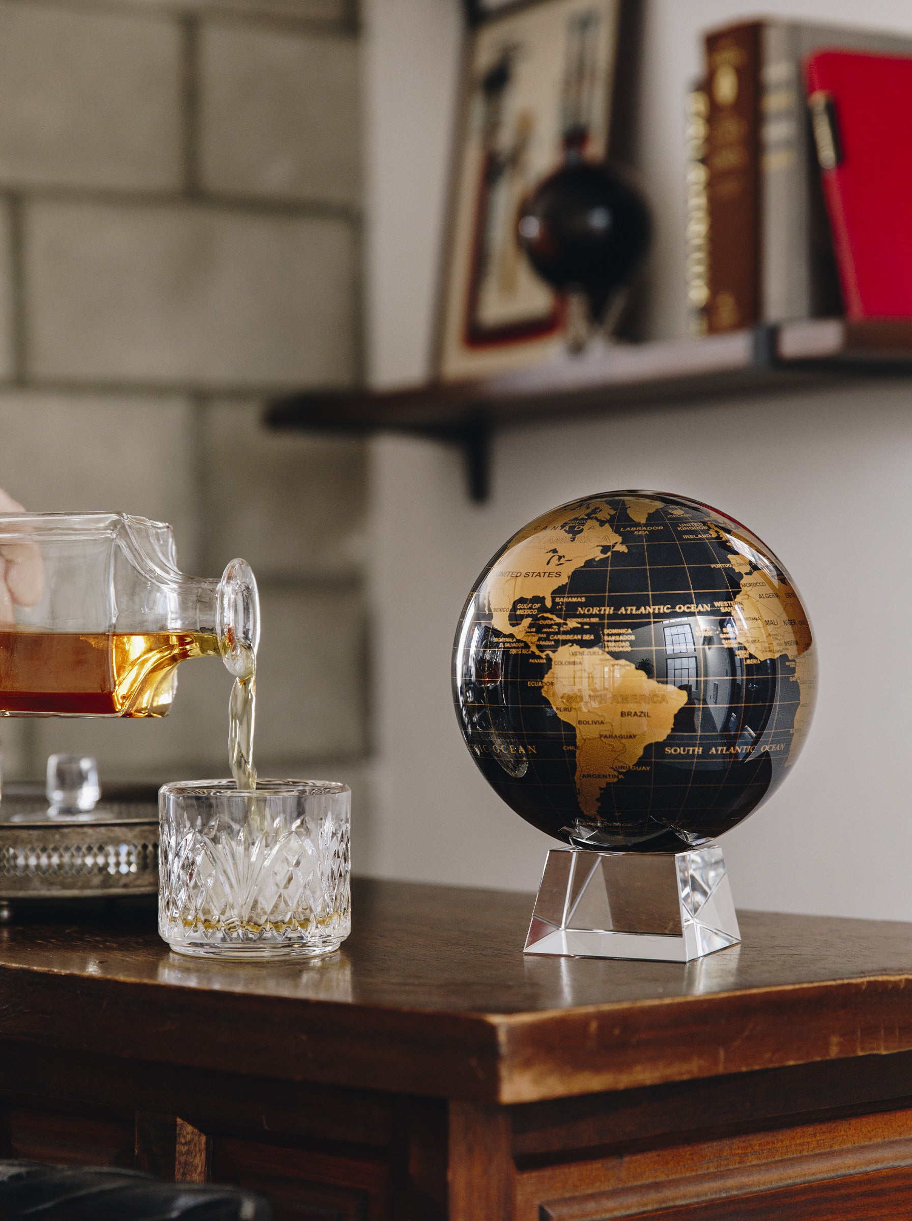 Black and gold MOVA globe styled in a modern industrial bar setting with luxury home decor accents