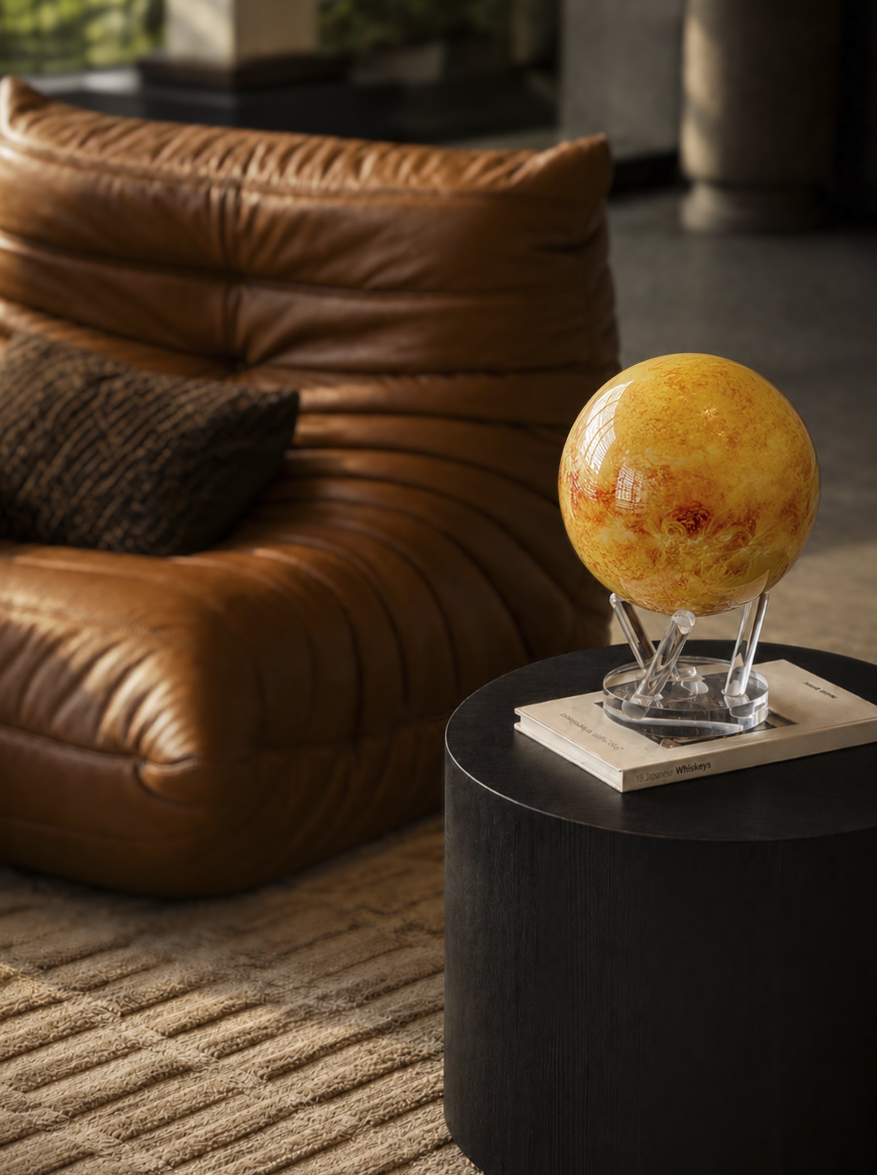 Sun MOVA globe displayed in a modern industrial living room with luxury leather furniture and warm decor styling