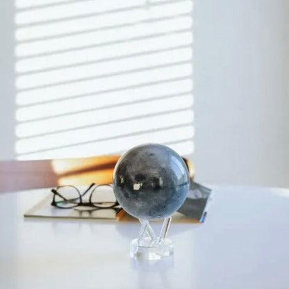 MOVA Moon rotating globe on desk with sunlight and glasses, sophisticated astronomy decoration and office ornament