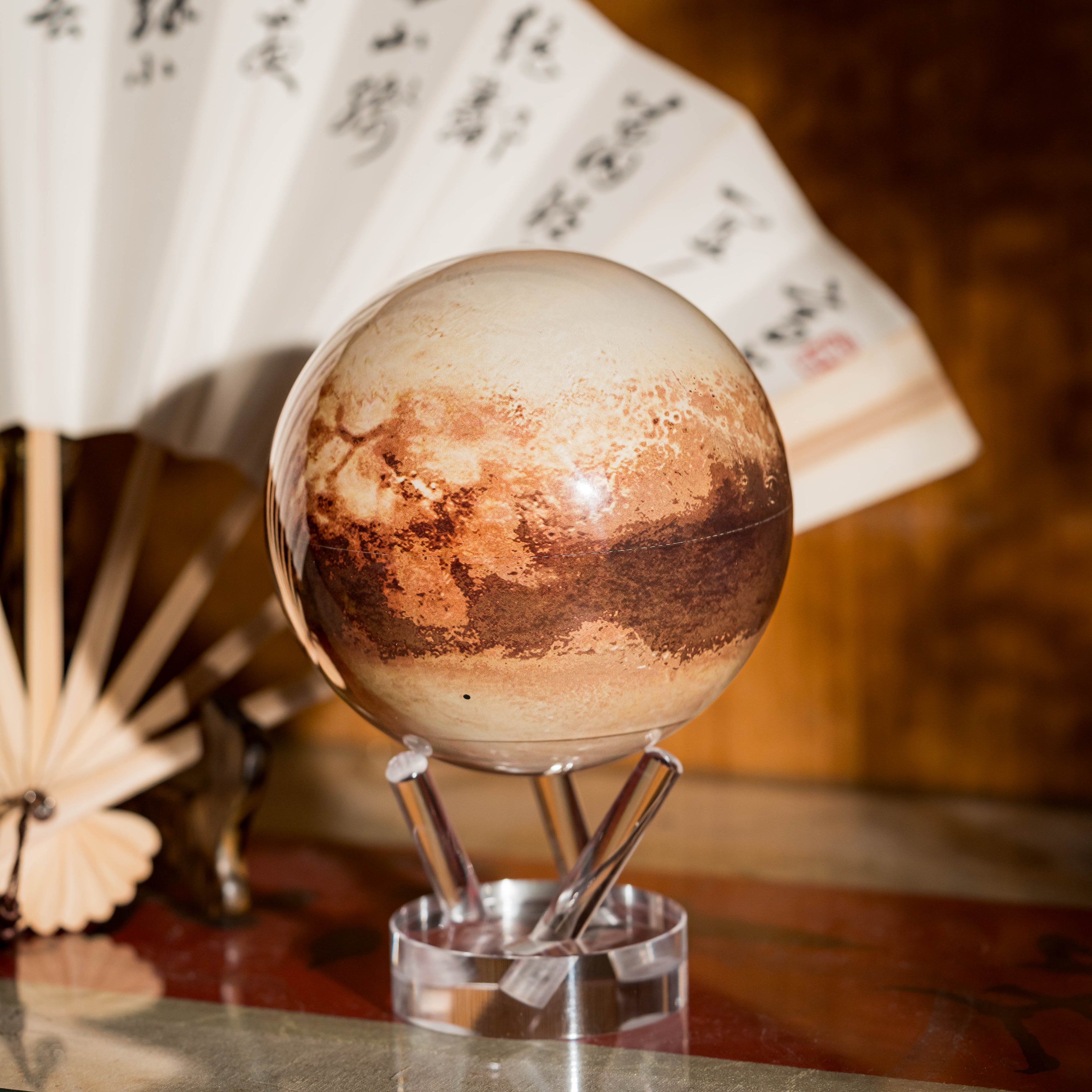 Pluto MOVA Globe with acrylic base and detailed Pluto surface artwork in a study setting