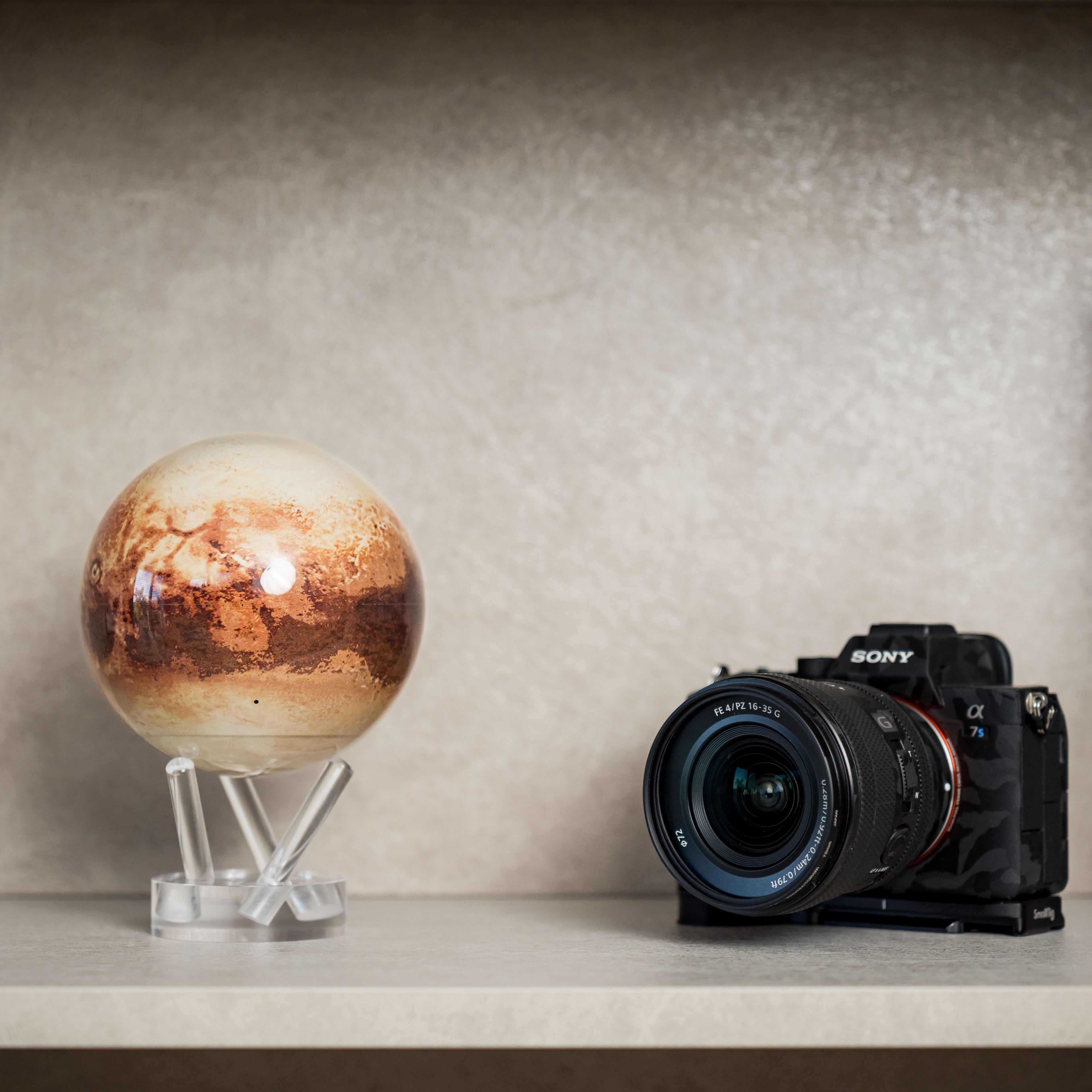 Pluto MOVA Globe displayed beside a camera, showcasing high-resolution NASA imagery of Pluto