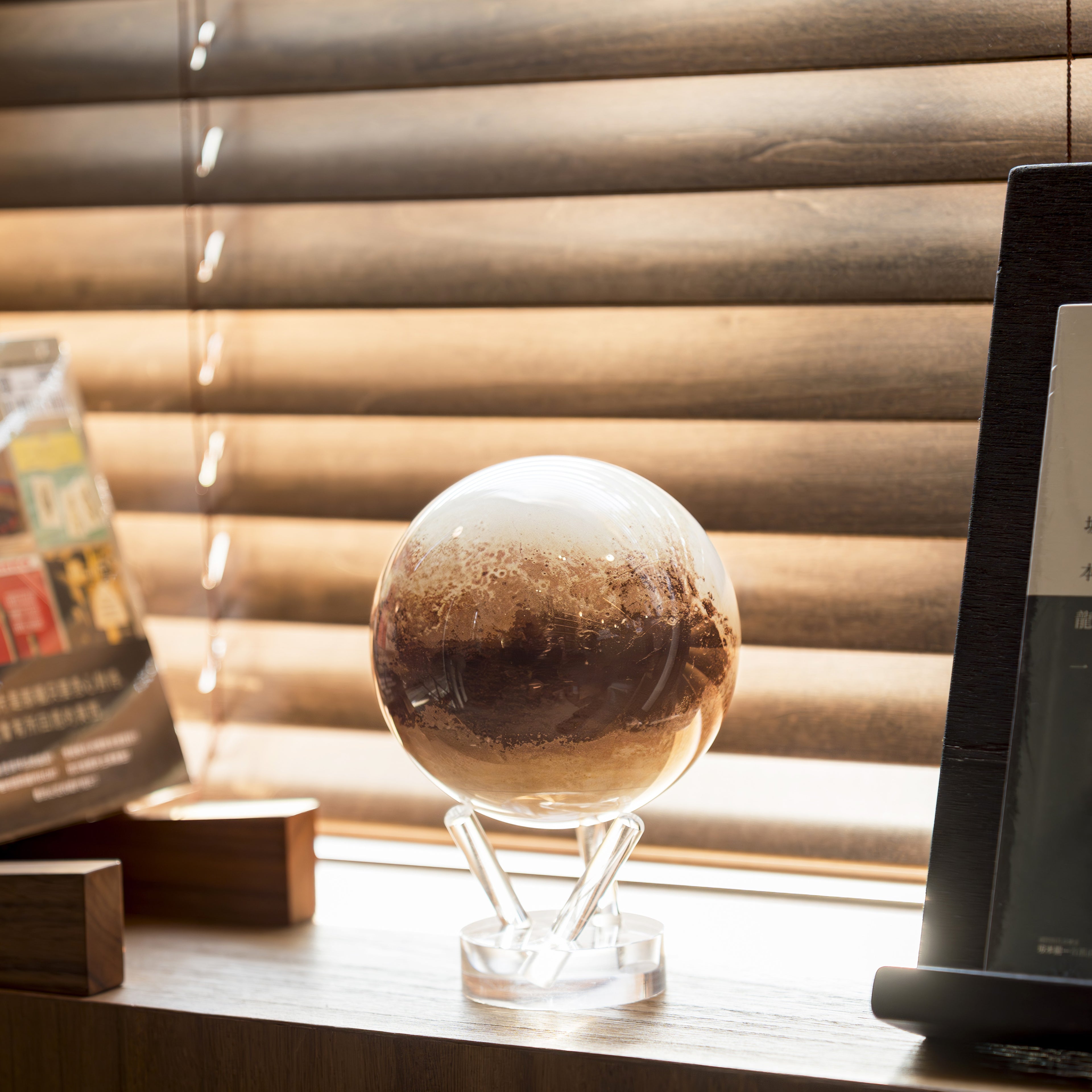 Pluto MOVA Globe on a windowsill with natural light, featuring Pluto&