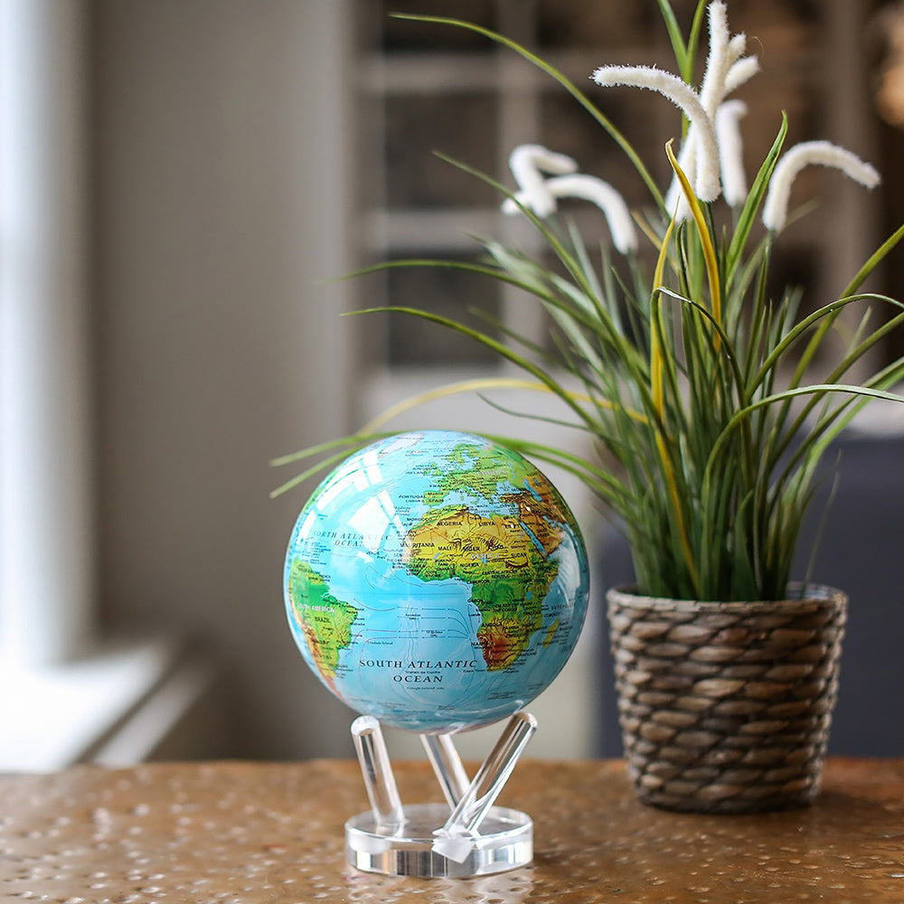 Ocean Blue Relief Map MOVA Globe beside potted plant tabletop decor