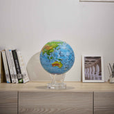 Ocean Blue Relief Map MOVA Globe on cabinet with books and framed artwork