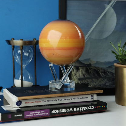 Saturn MOVA Globe displayed on bookshelf with hourglass and books