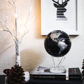 Jet Black & Silver MOVA Globe displayed on book with decorative accents