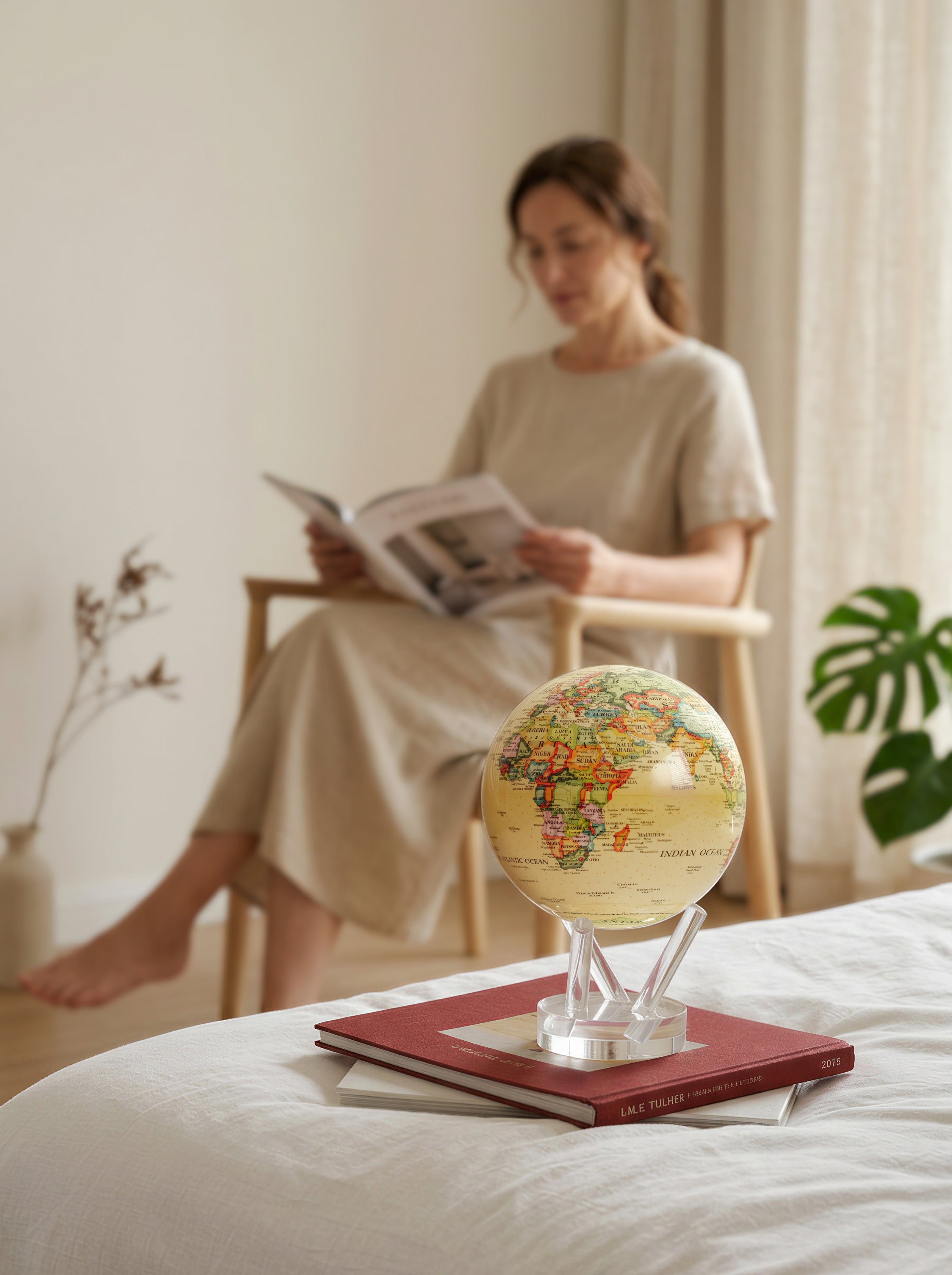 Antique yellow Cassini world map MOVA globe displayed in a calm modern minimalist bedroom with warm neutral decor styling
