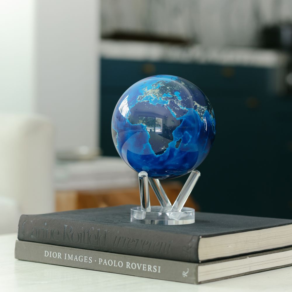 Earth at Night MOVA Globe displayed on stacked books in a modern home office