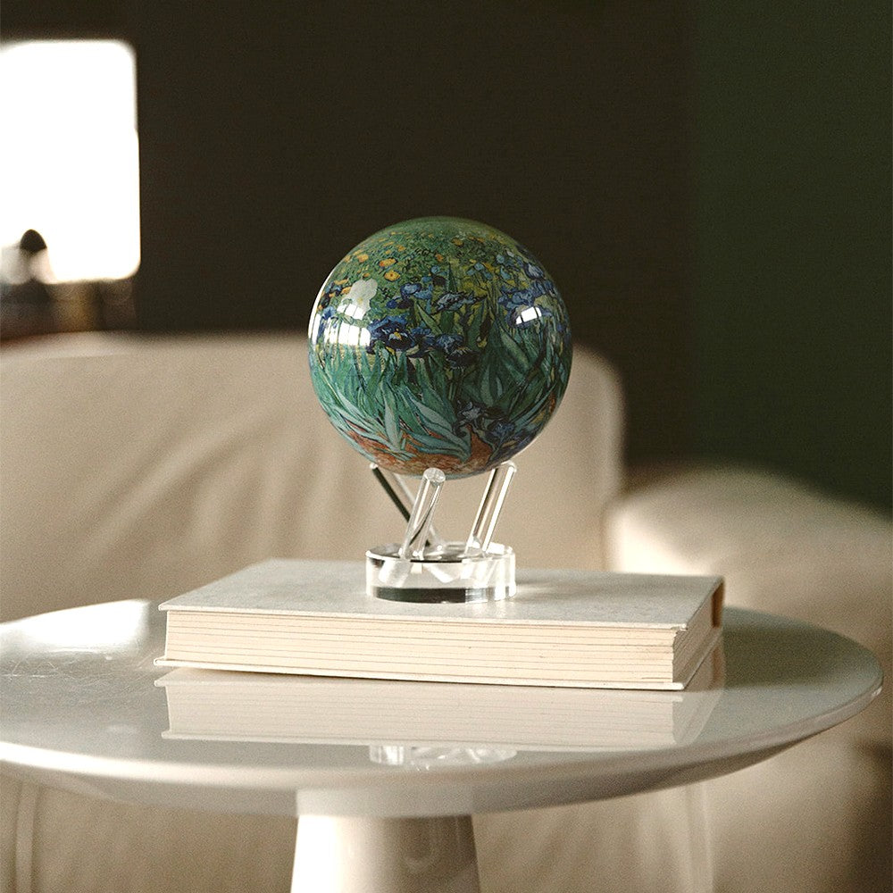 Van Gogh Irises MOVA Globe on stacked books, showcasing iconic floral artwork in a cozy room