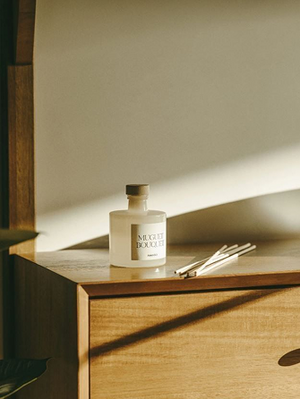 Minimalist reed diffuser on wooden cabinet with warm natural sunlight and modern Scandinavian home styling