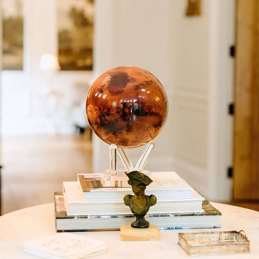 Mars MOVA globe with acrylic base styled on stacked books in a warm contemporary living space