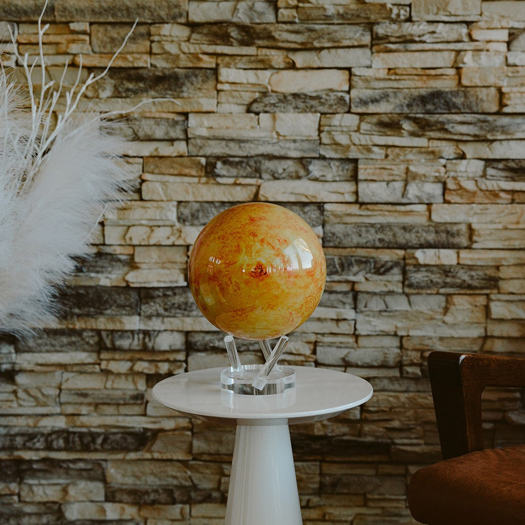 Sun MOVA Globe with acrylic base showcased on a side table against a stone accent wall in a modern living space