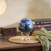 Van Gogh Starry Night MOVA Globe displayed on a wooden table with books and warm decor