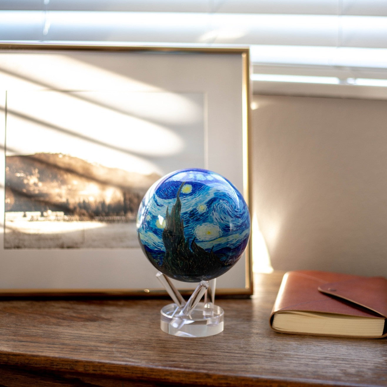 Van Gogh Starry Night MOVA Globe displayed beside framed artwork in a cozy living space