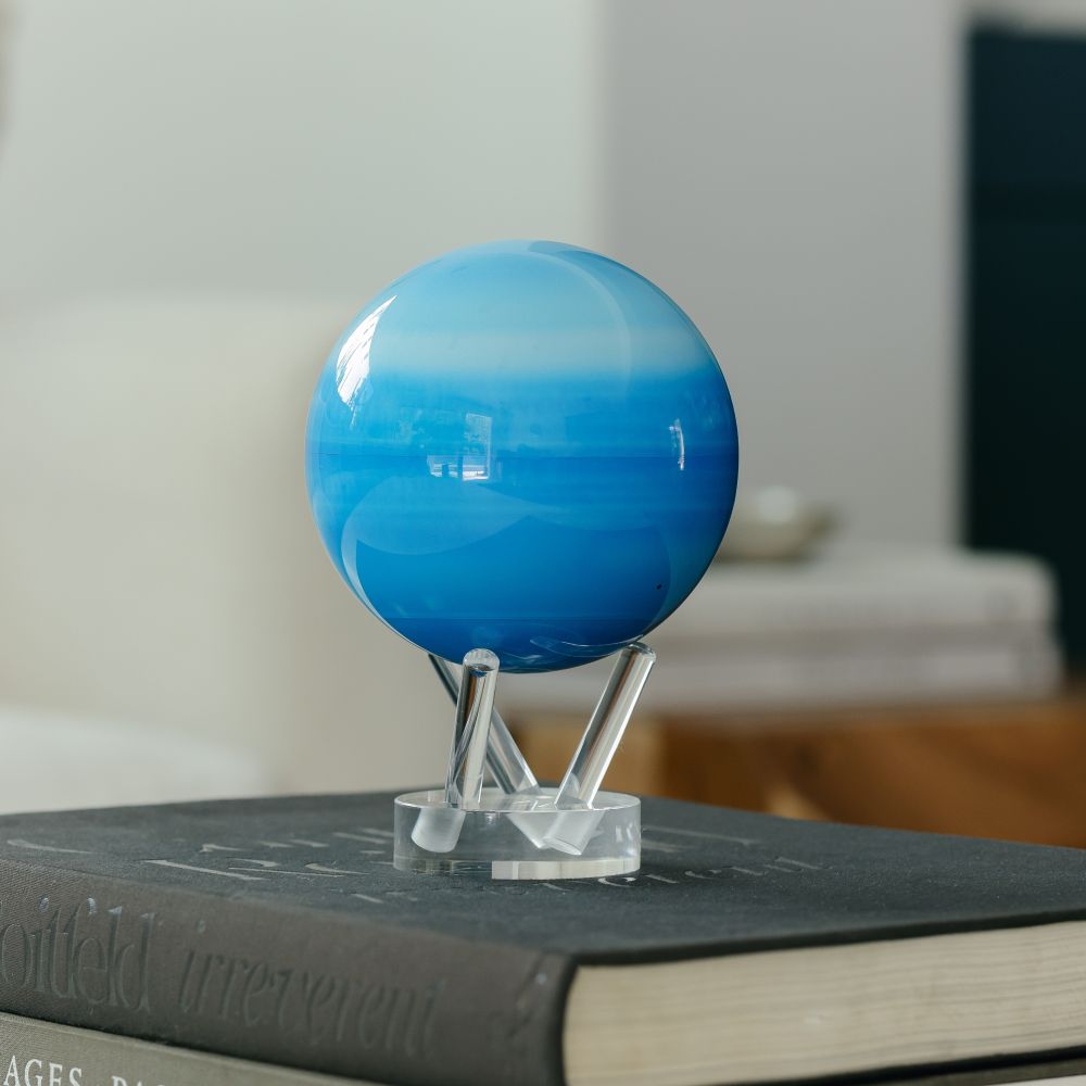 Uranus MOVA Globe with acrylic base displayed on stacked books, featuring NASA imagery and blue ice giant planet design for modern décor and space enthusiasts