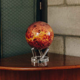 Venus MOVA Globe on acrylic base styled on a wooden cabinet with warm décor