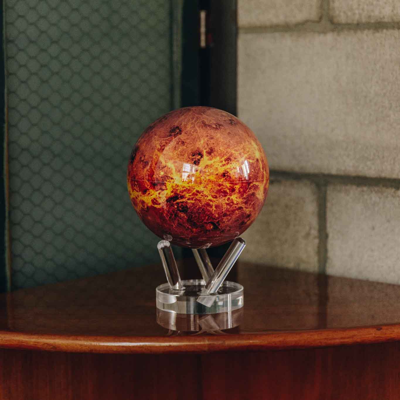 Venus MOVA Globe on acrylic base styled on a wooden cabinet with warm décor