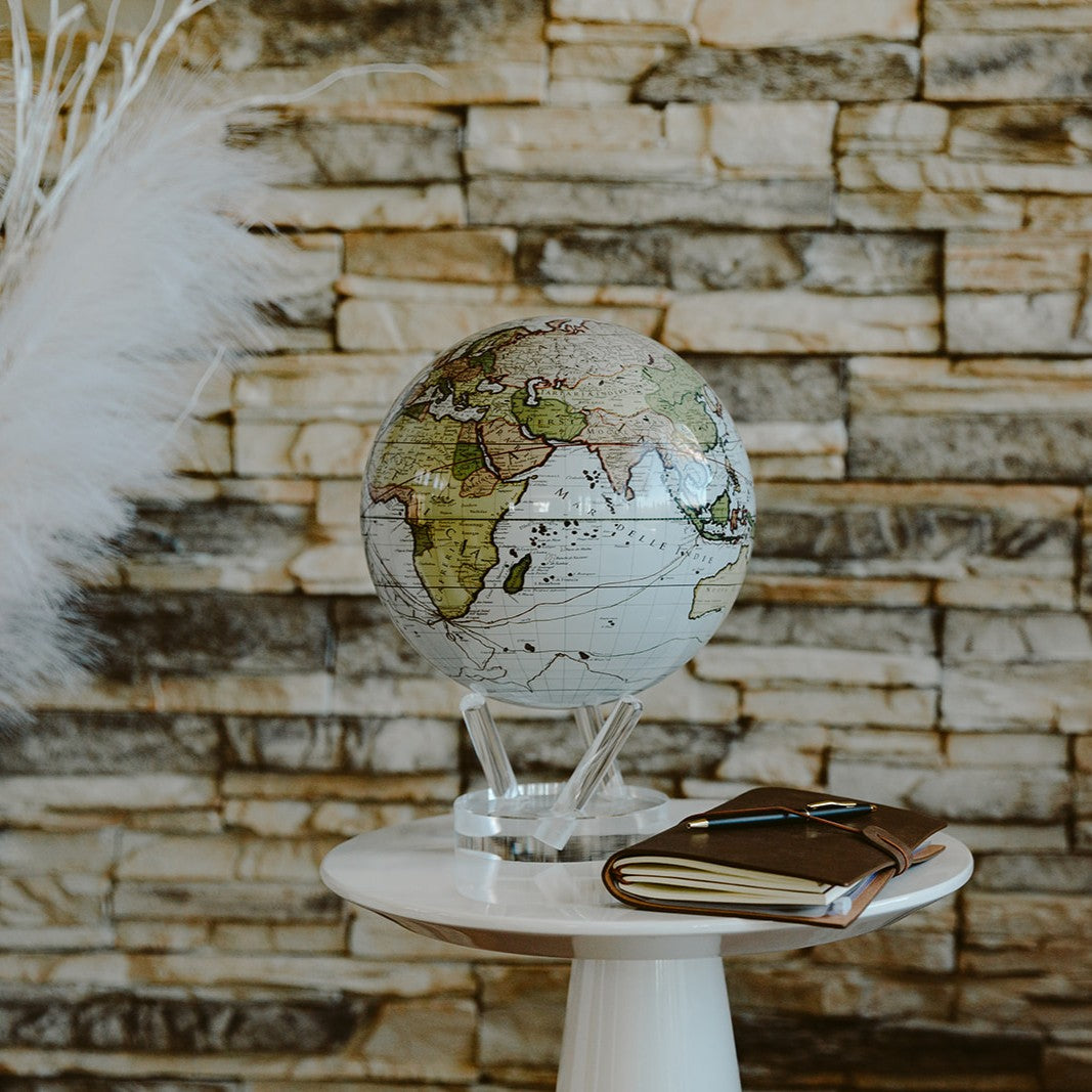 Antique Cassini White MOVA Globe on a side table against a stone accent wall
